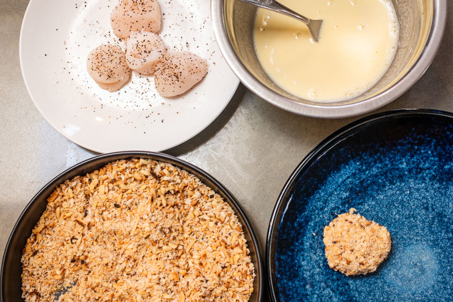 Coating Lighthouse Seafoods sea scallops in almond panko crust before pan frying.