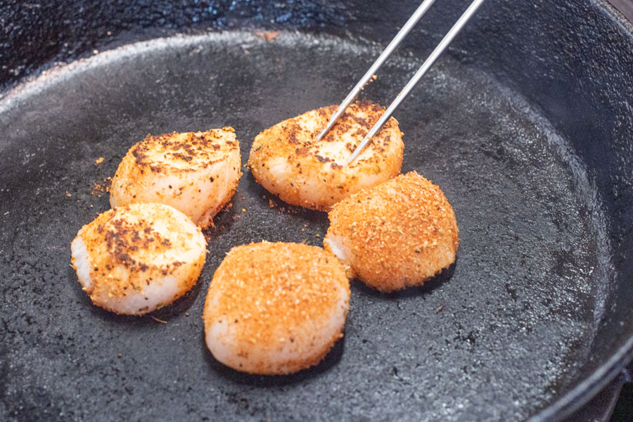Searing sea scallops in skillet for Lighthouse Seafoods seared scallops with crispy smashed potatoes seafood recipe.